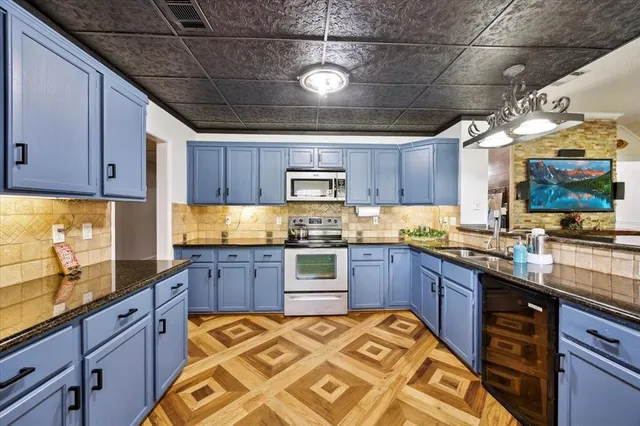 a kitchen with stainless steel appliances granite countertop wooden cabinets a stove and a sink