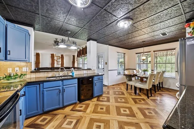 a living room with stainless steel appliances granite countertop a sink a stove top oven a dining table and chairs with wooden floor