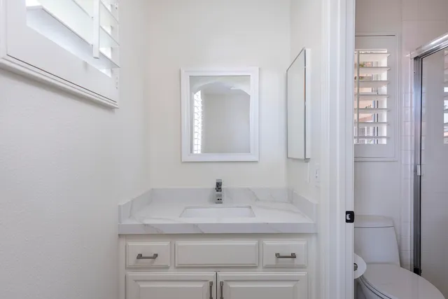 a bathroom with a granite countertop sink a toilet and a mirror