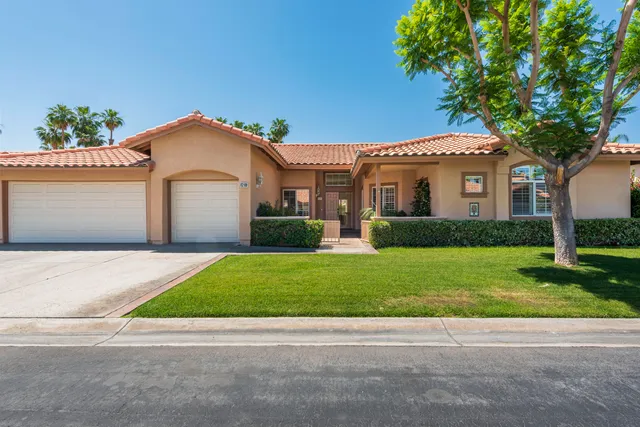 a front view of a house with a garden and trees
