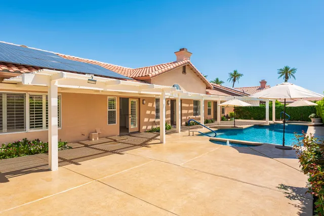 a view of a white house with swimming pool lawn chairs and a yard