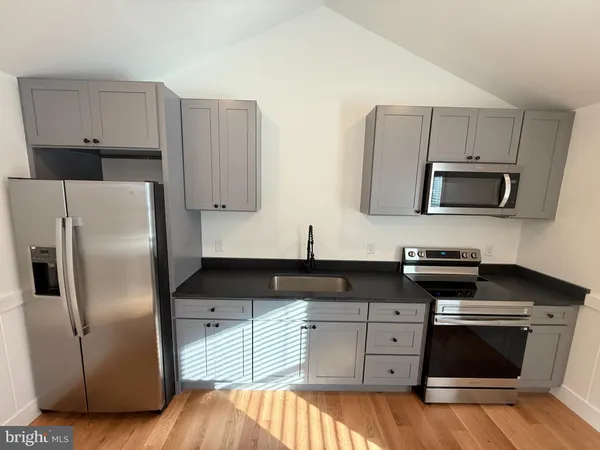 a kitchen with cabinets stainless steel appliances and wooden floor