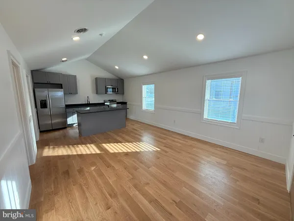 a kitchen with stainless steel appliances granite countertop a sink a stove top oven a wooden floors and a large window