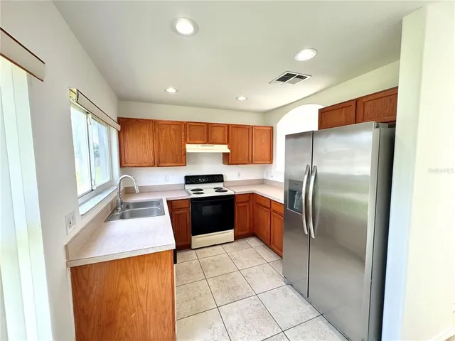 a kitchen with stainless steel appliances granite countertop a refrigerator and a stove top oven