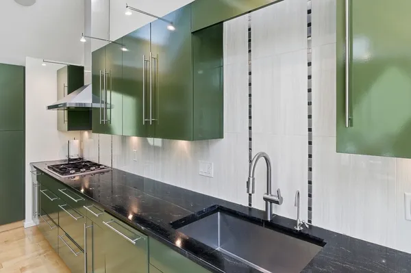 a living room with stainless steel appliances furniture a rug and a window