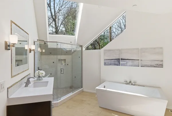 a spacious bathroom with a tub sink and mirror