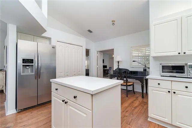 a kitchen with stainless steel appliances a stove a refrigerator a white table and chairs