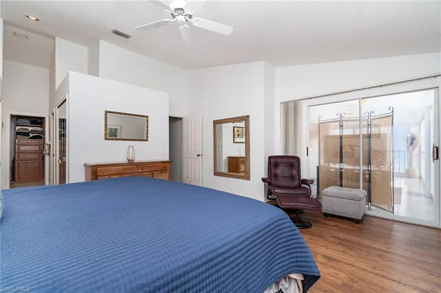 a bedroom with a bed couch and two large window