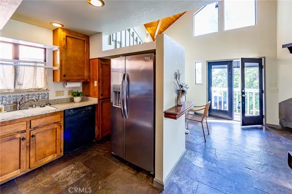 a kitchen with stainless steel appliances granite countertop a refrigerator a sink a stove and island with wooden floor