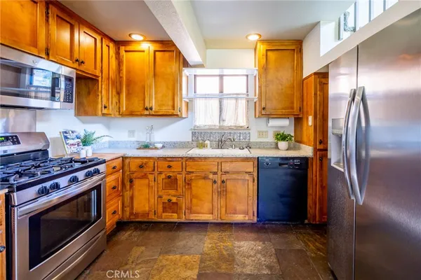 a kitchen with stainless steel appliances granite countertop a refrigerator a stove and a sink