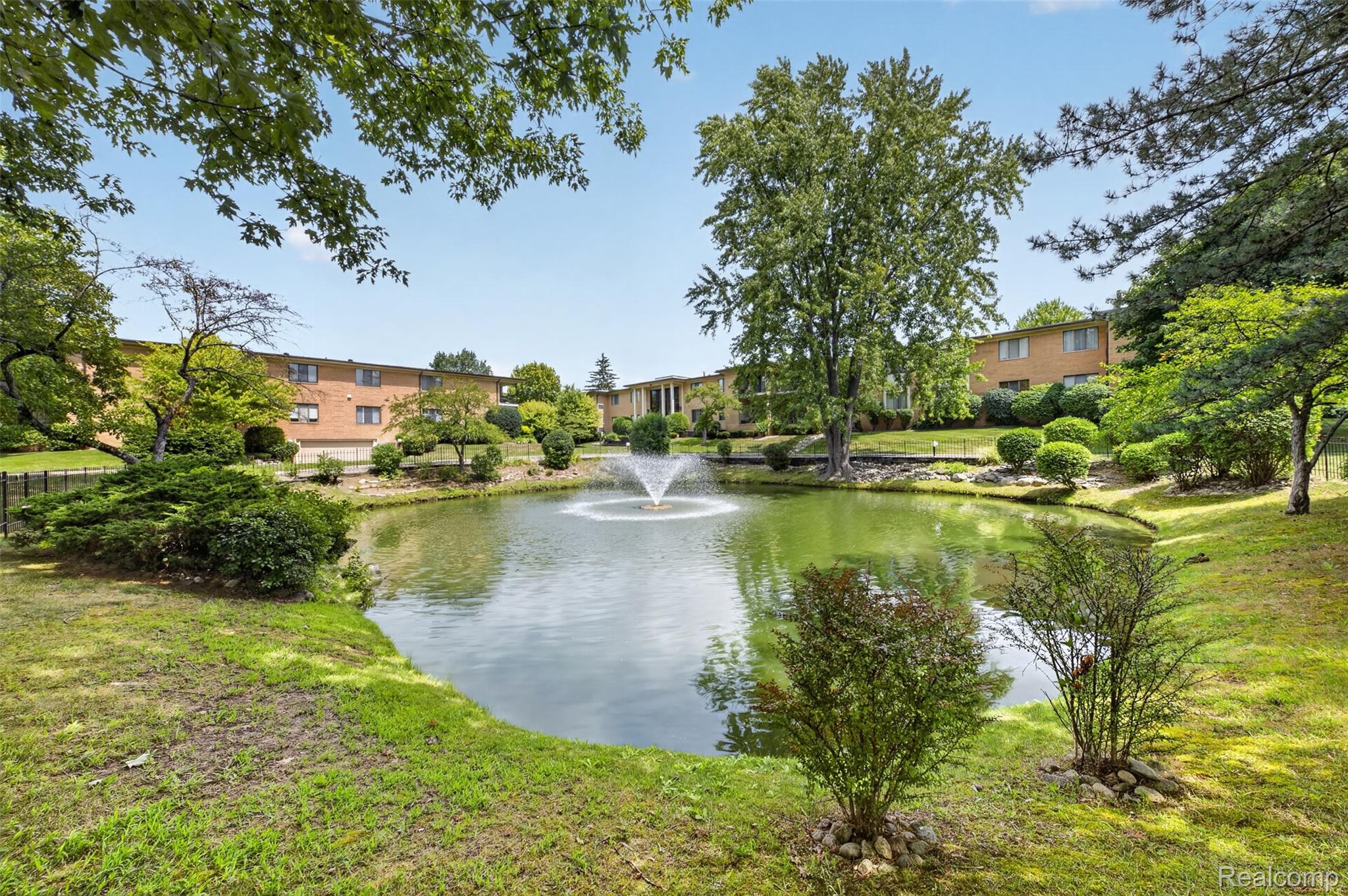 31915 West 14 Mile Road Farmington, MI 48334 - Photo 5 of 47 Landscaped grounds featuring a central pond with a fountain, mature trees, and established shrubbery