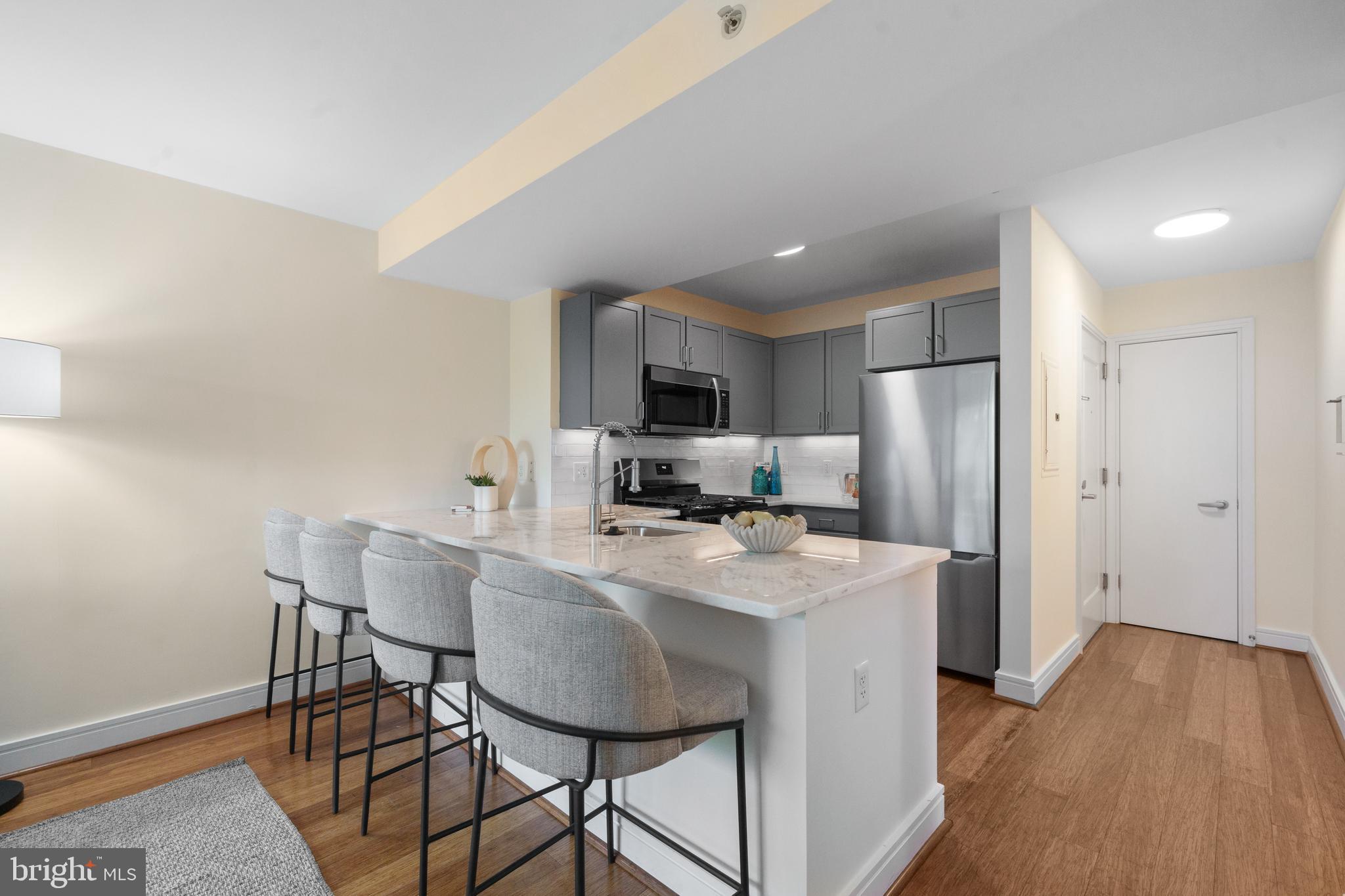 800 4th Street Southwest, Unit S421 Washington, DC 20024 - Photo 8 of 30 a kitchen with stainless steel appliances granite countertop a stove a refrigerator a sink a dining table and chairs with wooden floor