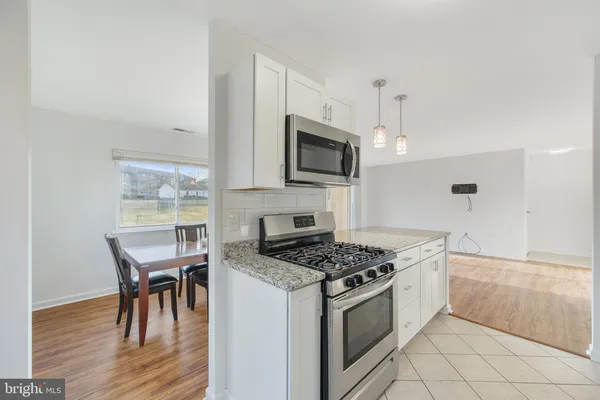 a kitchen with granite countertop a stove a sink and chairs
