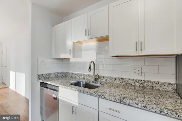 a kitchen with granite countertop white cabinets and a sink