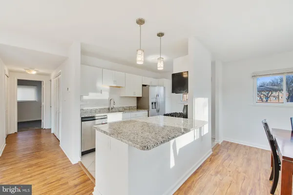 a view of a kitchen with kitchen island a sink and wooden floor