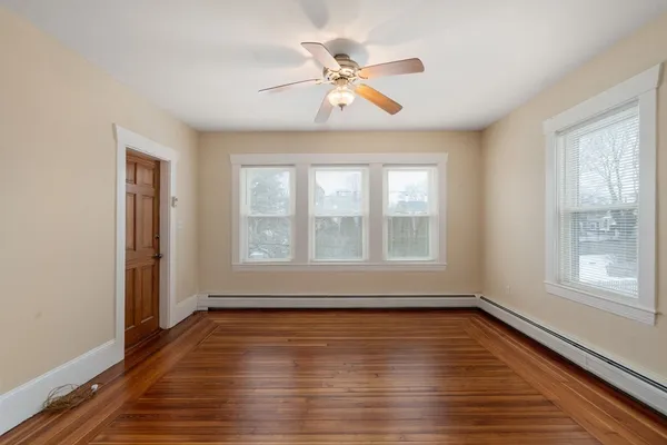 a view of an empty room with wooden floor and a window