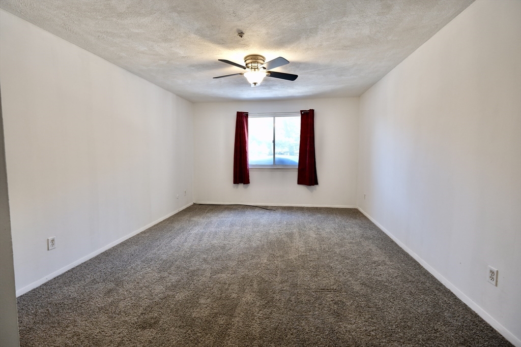 232 Canton Street, Unit 308 Randolph, MA 02368 - Photo 21 of 41 an empty room with a chandelier fan and windows