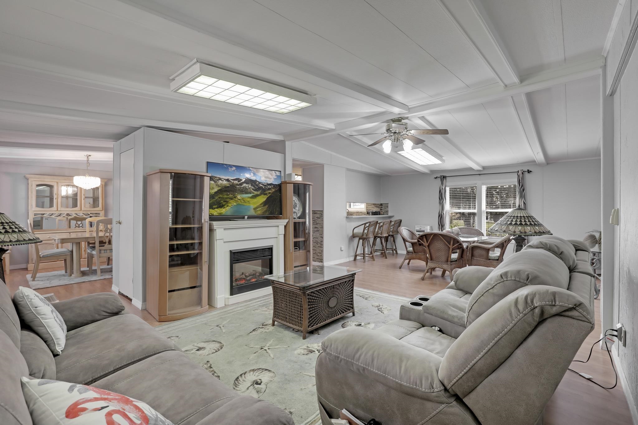 6901 Catlett Road St. Augustine, FL 32095 - Photo 16 of 74 Living room featuring wood finished floors, a glass covered fireplace, beam ceiling, and a ceiling fan