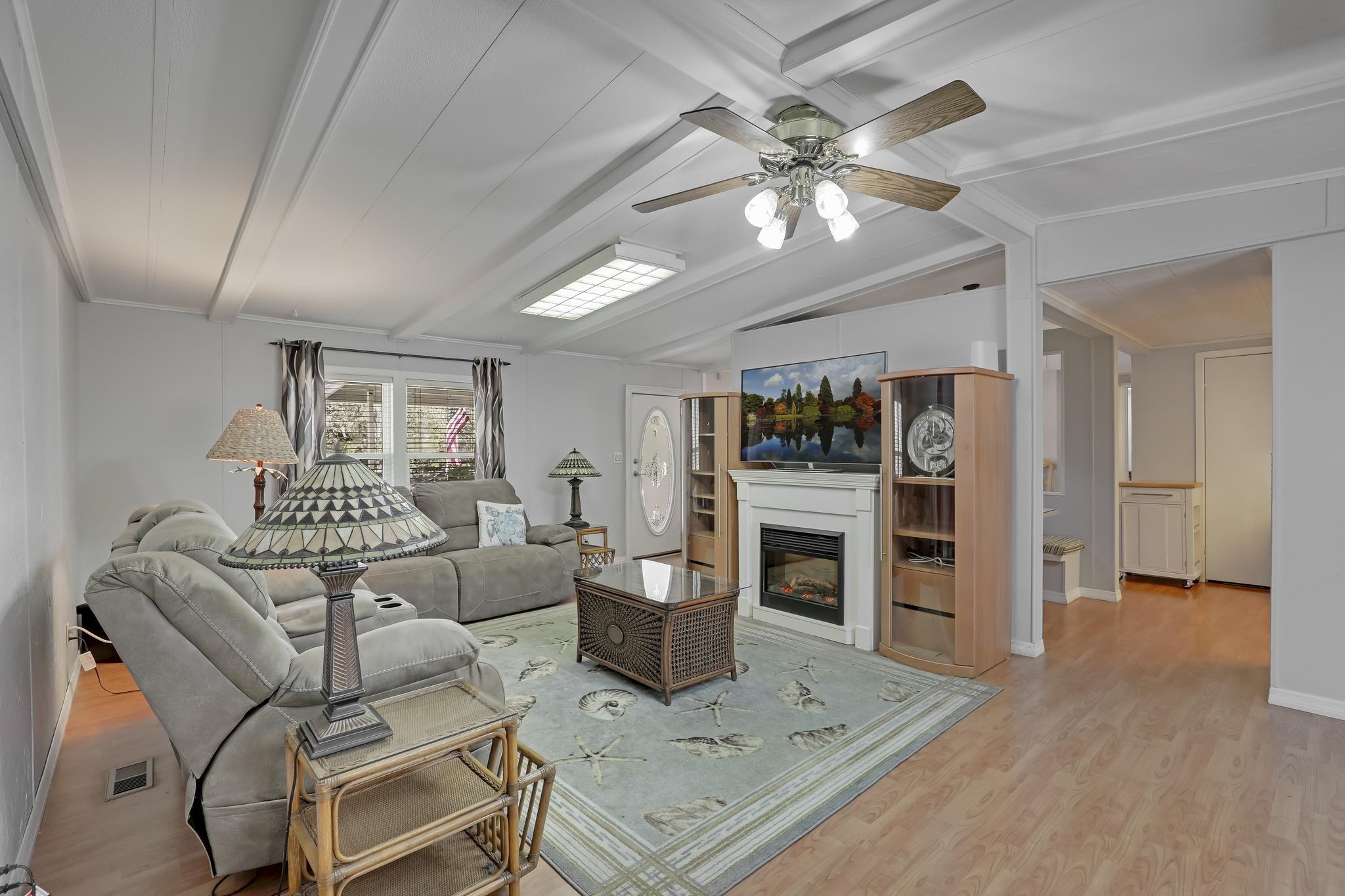 6901 Catlett Road St. Augustine, FL 32095 - Photo 3 of 74 Living area with light wood-style floors, vaulted ceiling with beams, a glass covered fireplace, ceiling fan, and ornamental molding