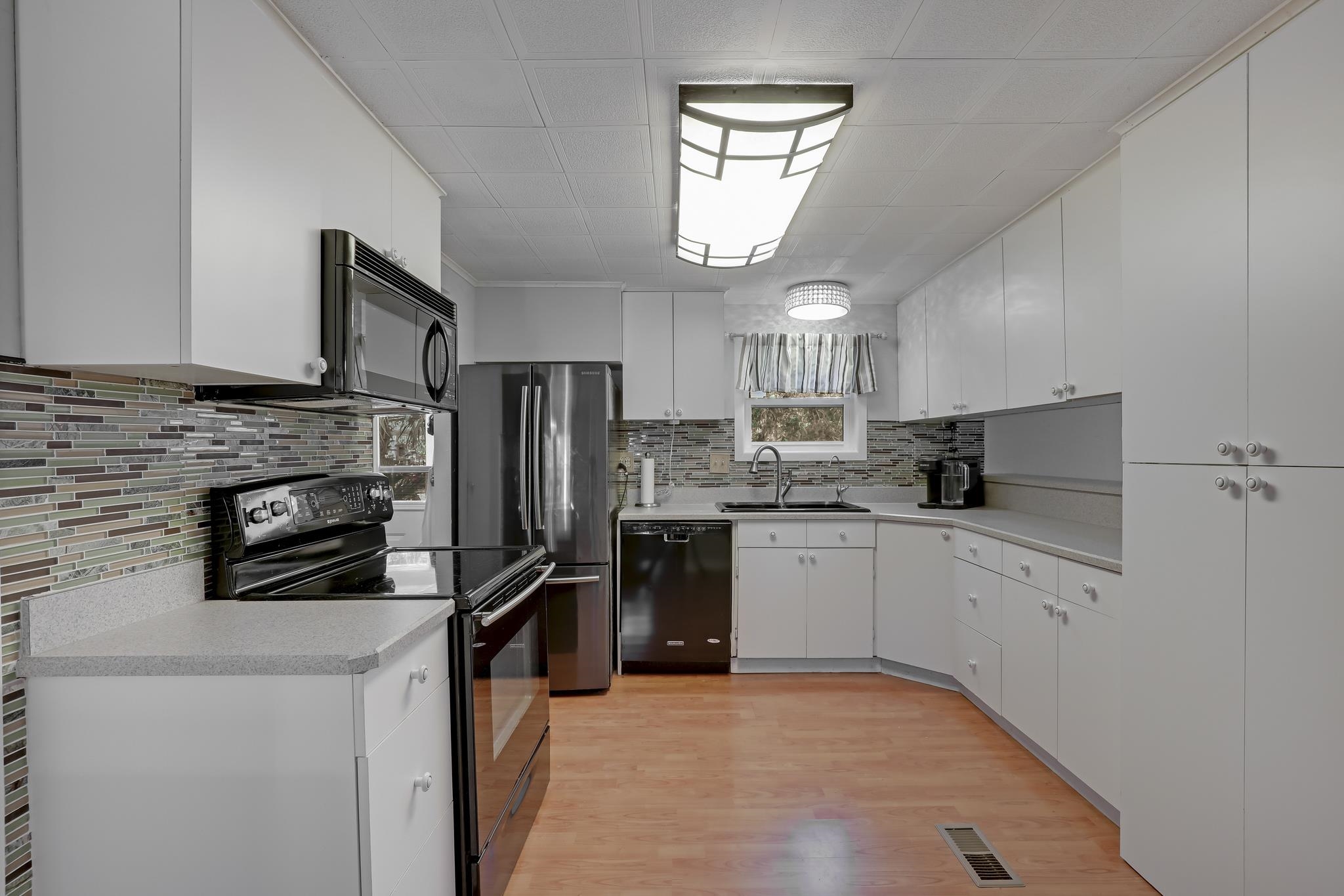 6901 Catlett Road St. Augustine, FL 32095 - Photo 31 of 74 Kitchen featuring black appliances, light countertops, white cabinets, light wood-type flooring, and decorative backsplash