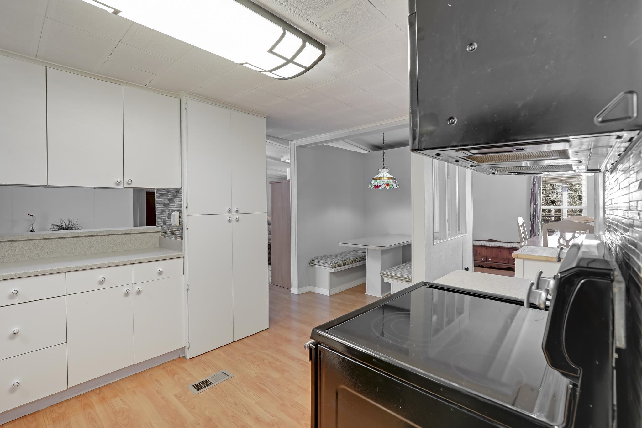 6901 Catlett Road St. Augustine, FL 32095 - Photo 35 of 74 Kitchen with exhaust hood, black / electric stove, decorative light fixtures, white cabinets, and light wood finished floors
