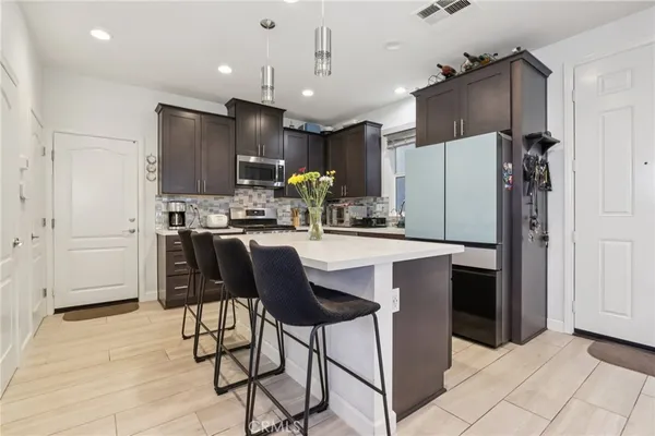 a kitchen with stainless steel appliances kitchen island granite countertop a stove a sink and a refrigerator