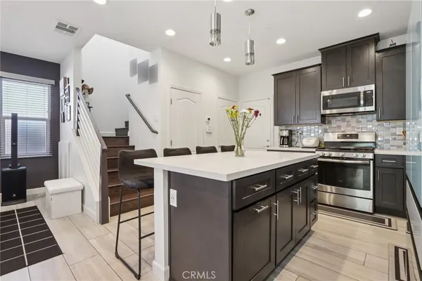 a kitchen with kitchen island a sink a stove and chairs