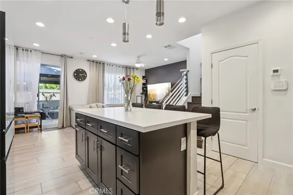a kitchen with stainless steel appliances granite countertop a refrigerator a sink dishwasher a dining table and chairs with wooden floor
