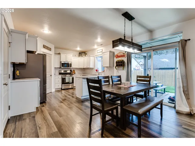 a kitchen with stainless steel appliances kitchen island granite countertop a table chairs and a refrigerator
