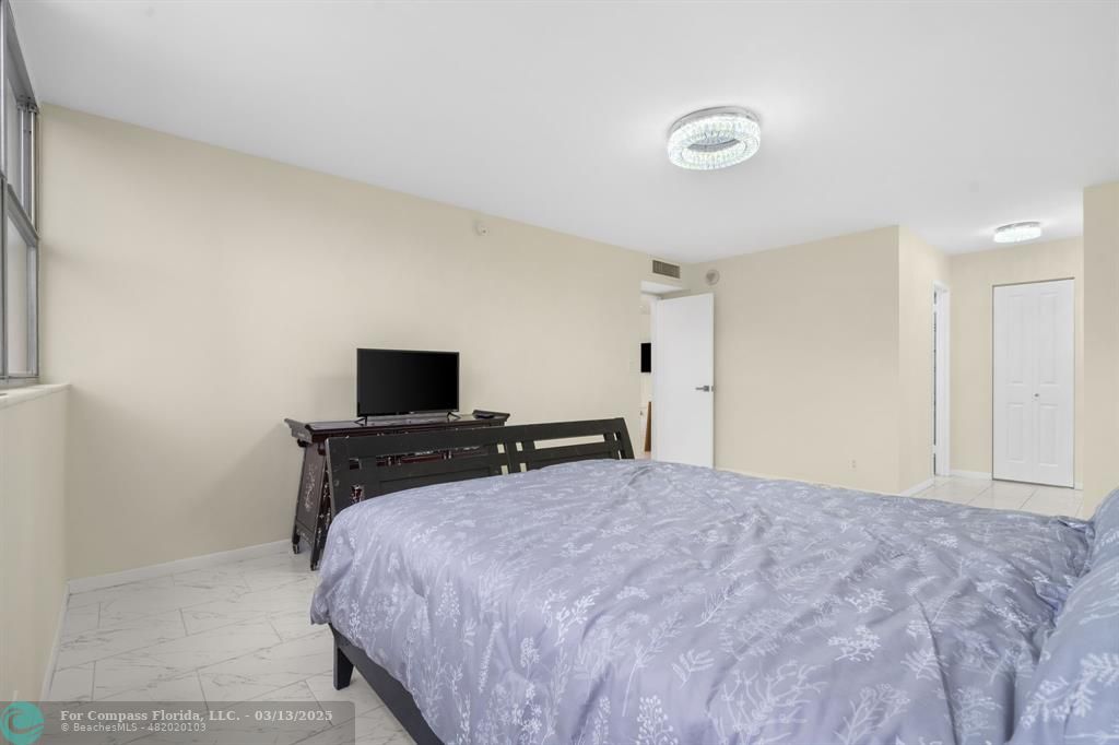 100 Golden Isles Drive, Unit 313 Hallandale Beach, FL 33009 - Photo 13 of 33 a bedroom with a bed and a flat screen tv