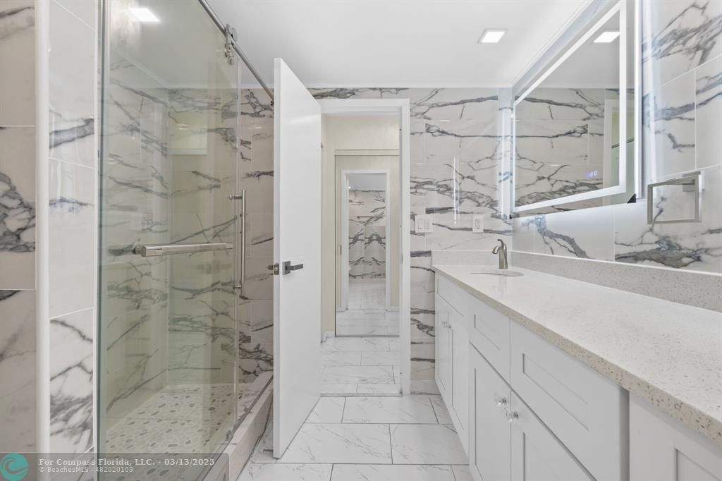 100 Golden Isles Drive, Unit 313 Hallandale Beach, FL 33009 - Photo 16 of 33 a bathroom with a shower sink and mirror