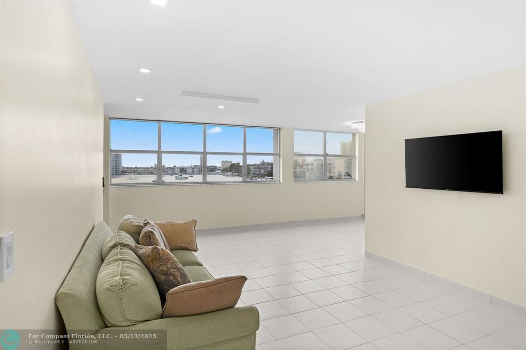 100 Golden Isles Drive, Unit 313 Hallandale Beach, FL 33009 - Photo 20 of 33 a living room with stainless steel appliances a couch and a flat screen tv