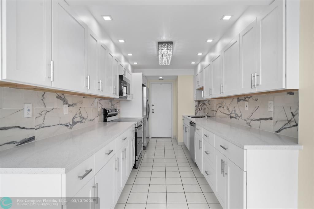 100 Golden Isles Drive, Unit 313 Hallandale Beach, FL 33009 - Photo 23 of 33 a kitchen with granite countertop a sink and cabinets