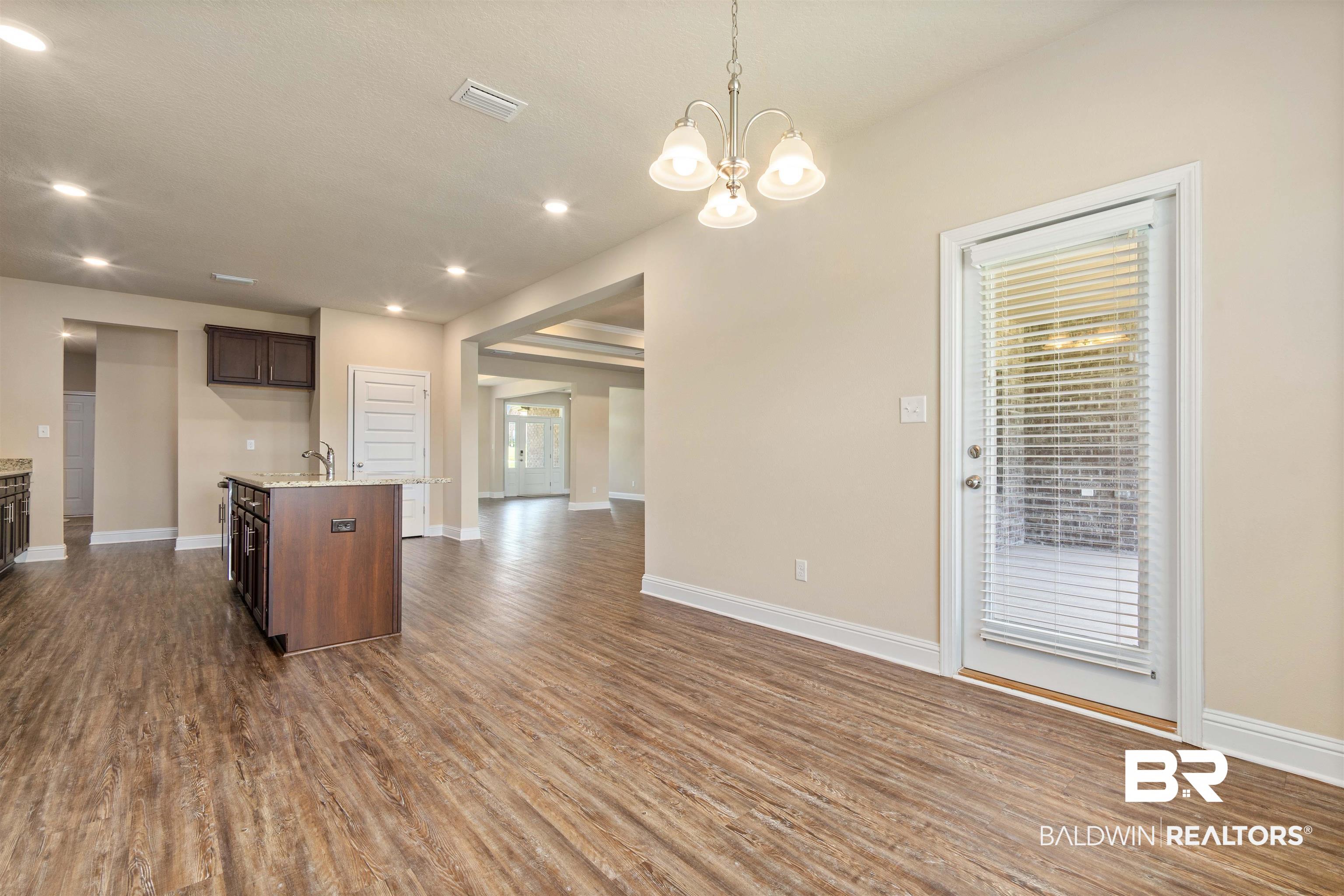 1864 Gwin Court Mobile, AL 36695 - Photo 13 of 37 Kitchen with hardwood / wood-style floors, dark brown cabinets, sink, an island with sink, and pendant lighting