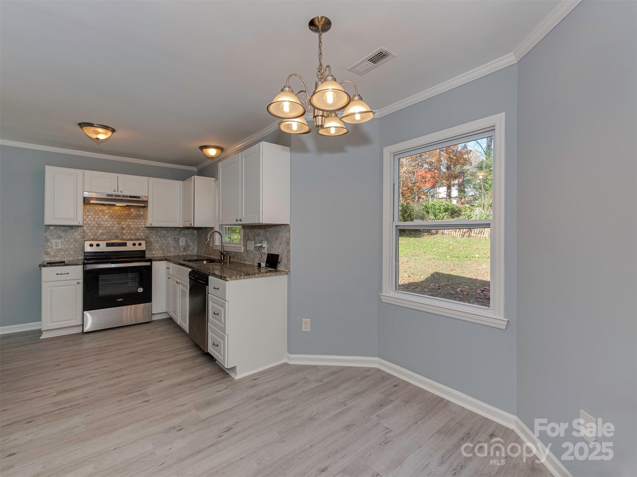 7413 Lockmont Drive Charlotte, NC 28212 - Photo 12 of 42 a kitchen with stainless steel appliances granite countertop a stove top oven a sink dishwasher a dining table and chairs with wooden floor