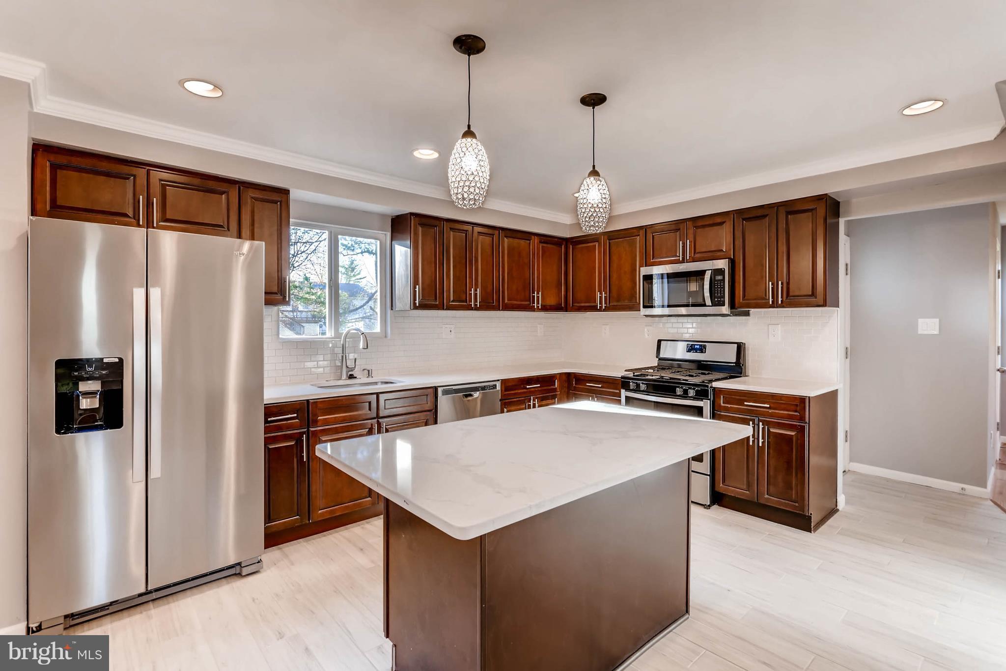 3935 Nemo Road Randallstown, MD 21133 - Photo 7 of 23 a kitchen with stainless steel appliances granite countertop a refrigerator a sink dishwasher a stove top oven a kitchen island and couches with wooden floor