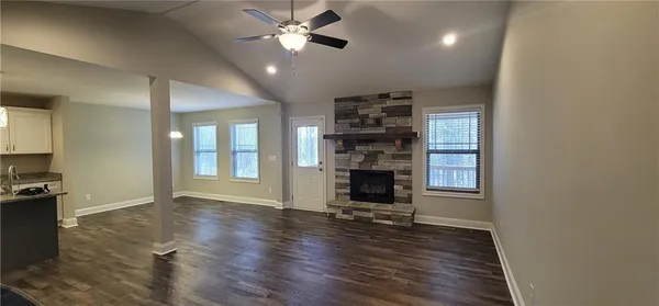 an empty room with wooden floor fireplace and windows
