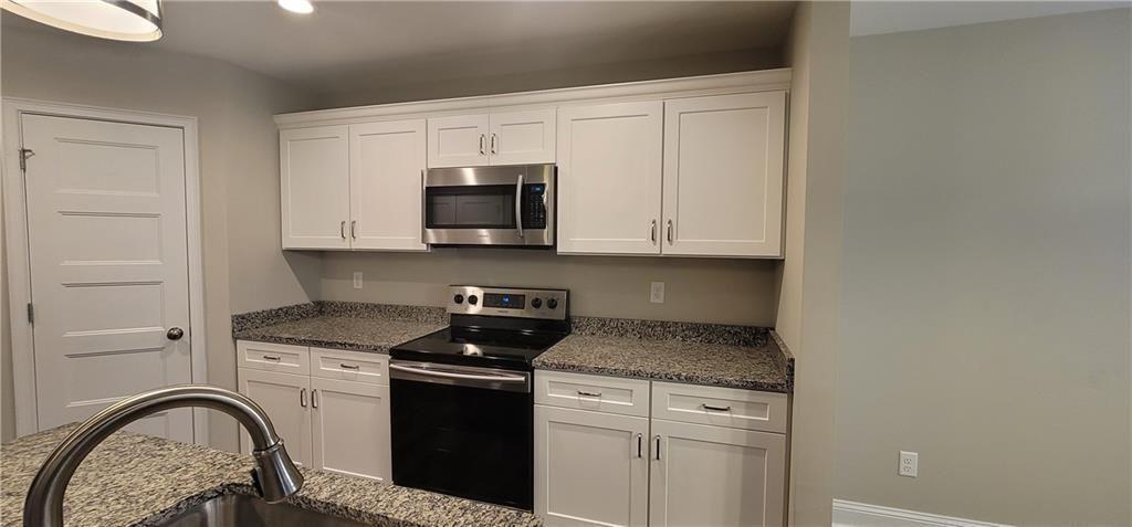 123 Ridge Crest Court Ellijay, GA 30540 - Photo 28 of 34 a kitchen with stainless steel appliances granite countertop white cabinets a sink a stove and a microwave