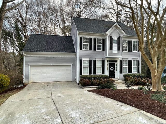 a front view of a house with yard and parking