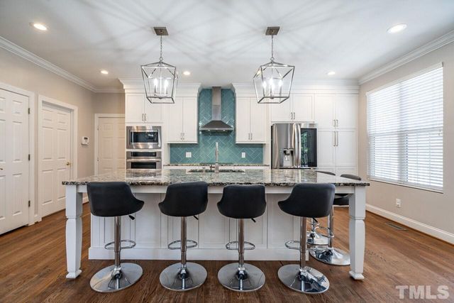 a kitchen with stainless steel appliances granite countertop a dining table chairs and chandelier