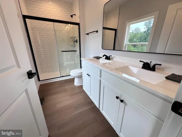 a bathroom with a double vanity sink a mirror and a shower