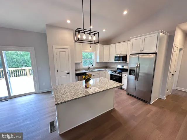 a kitchen with stainless steel appliances granite countertop a refrigerator a sink dishwasher a refrigerator a stove and white cabinets with wooden floor