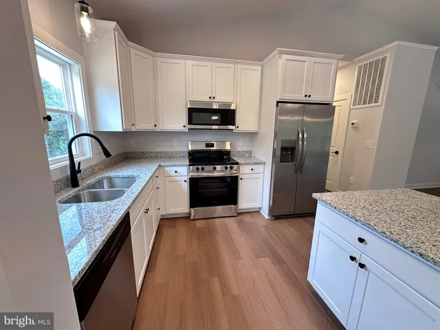 a kitchen with granite countertop a refrigerator stove and sink