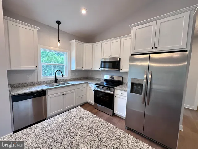 a kitchen with stainless steel appliances granite countertop a refrigerator sink and stove