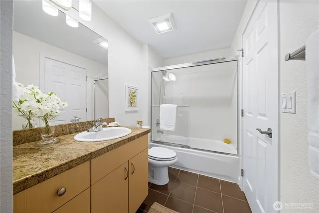 a spacious bathroom with a granite countertop sink toilet mirror and shower
