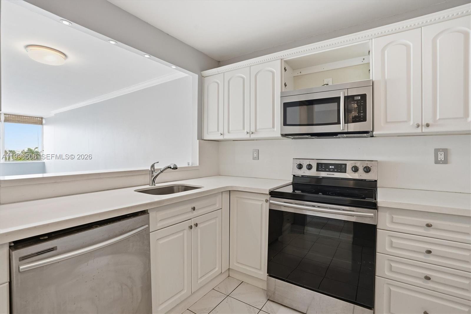 8233 Harding Avenue, Unit 504 Miami Beach, FL 33141 - Photo 11 of 24 a kitchen with white cabinets stainless steel appliances and sink
