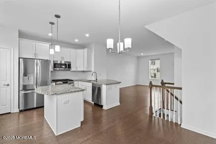 a kitchen with stainless steel appliances granite countertop a refrigerator a sink dishwasher a stove and a dining table with wooden floor