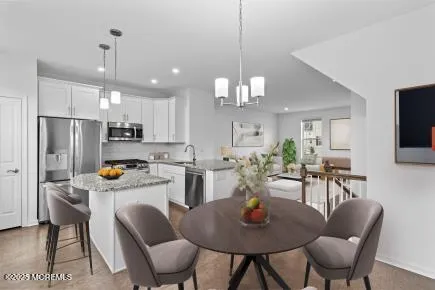 a kitchen with stainless steel appliances kitchen island granite countertop a dining table chairs refrigerator and cabinets