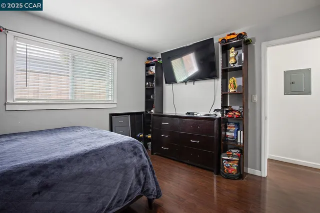 a bedroom with a bed window and a flat tv screen on wall