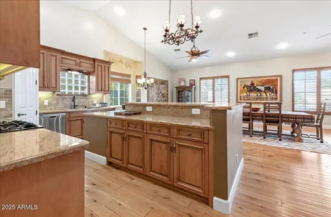 a kitchen with stainless steel appliances granite countertop a stove a sink dishwasher a refrigerator and wooden cabinets with wooden floor